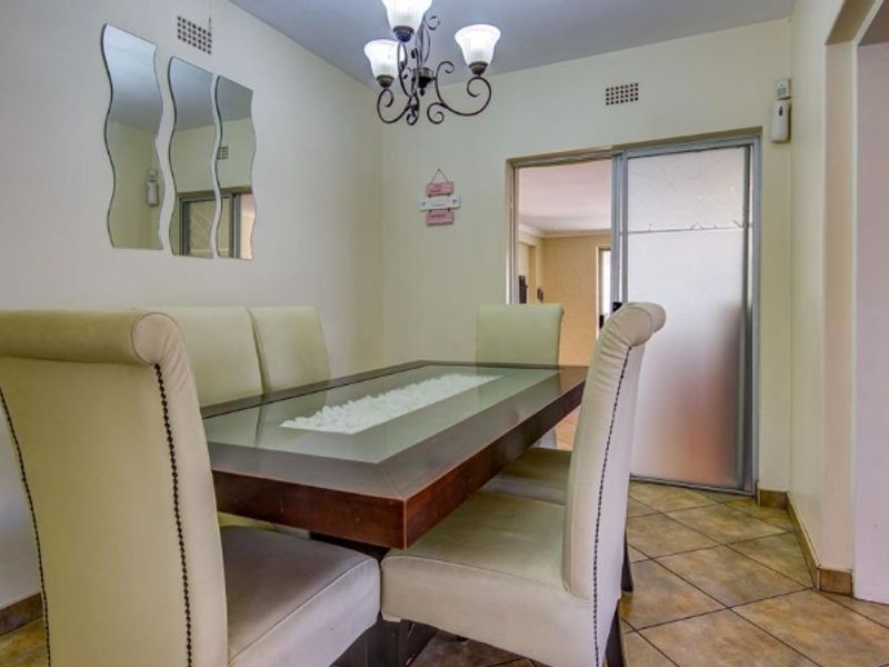 A functional dining area featuring tiled flooring, a sliding glass door providing access to adjacent spaces, and a central ceiling light fixture.