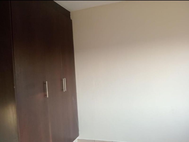A bedroom interior featuring dark wood built-in cupboards with modern metal handles.
