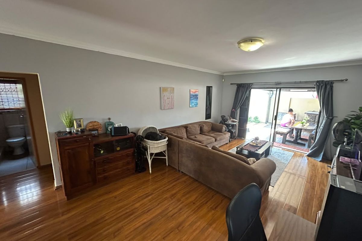 Spacious living room featuring laminate flooring and large sliding glass doors that provide direct access to the outdoor patio area.