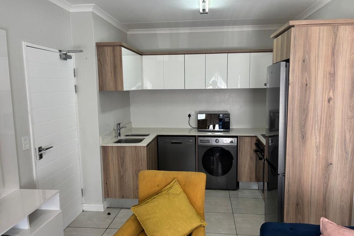 A compact, modern kitchen featuring wood-grain and white cabinetry, tiled flooring, and integrated appliance spaces, offering a clean and functional layout.
