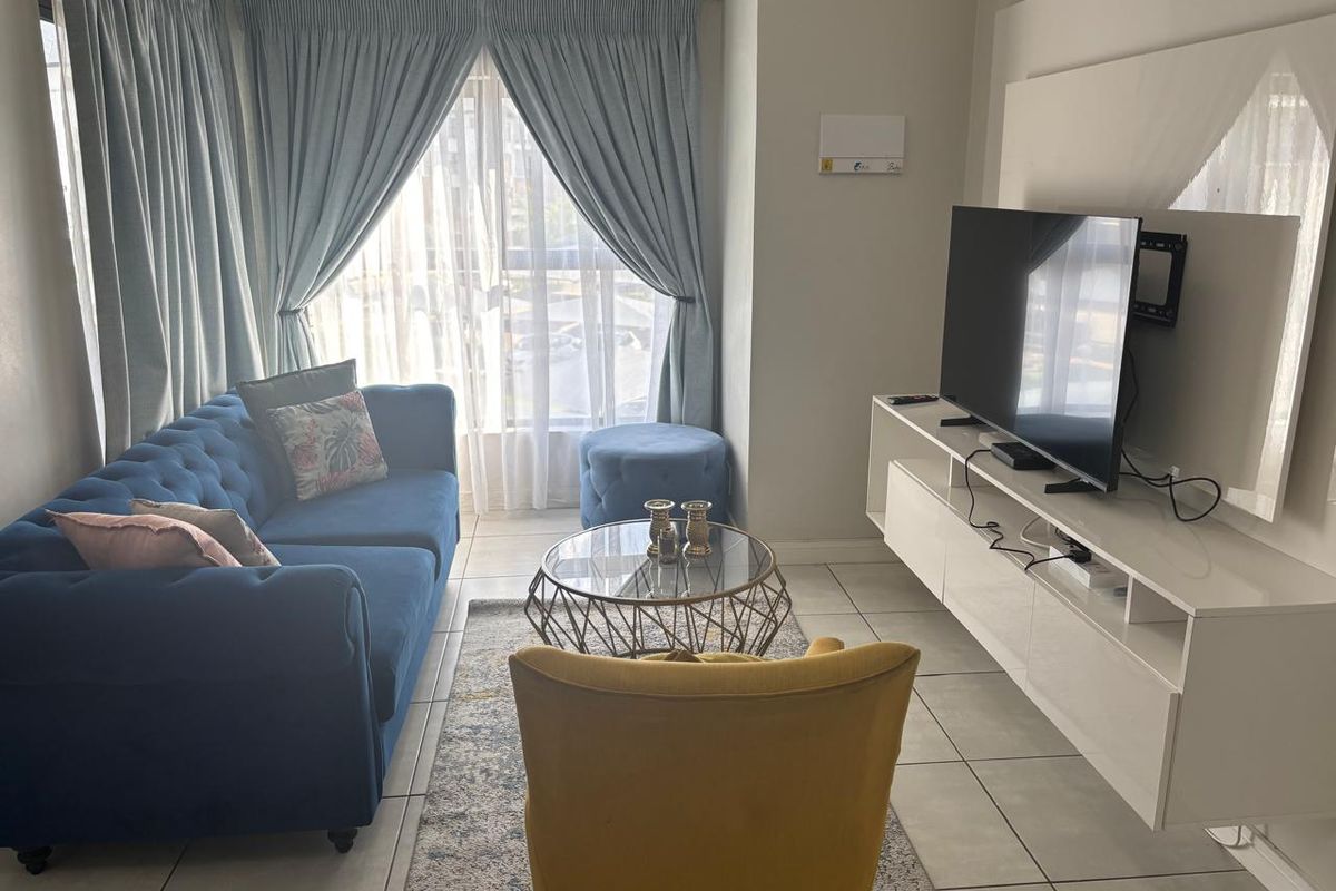 A well-lit living room featuring tiled flooring and large windows with curtains, providing a comfortable and functional space.