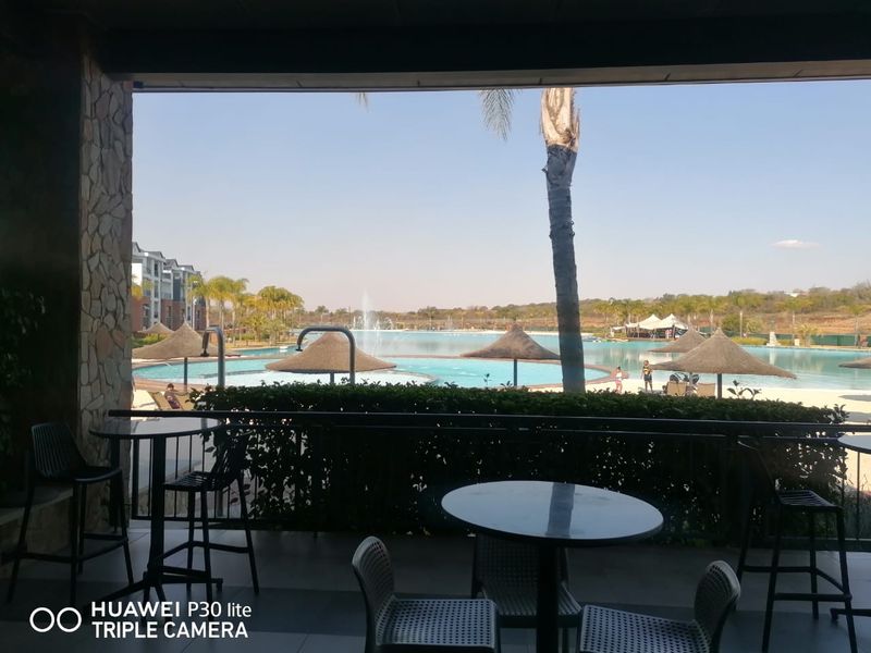 Covered patio area overlooking a large communal swimming pool and landscaped estate grounds.