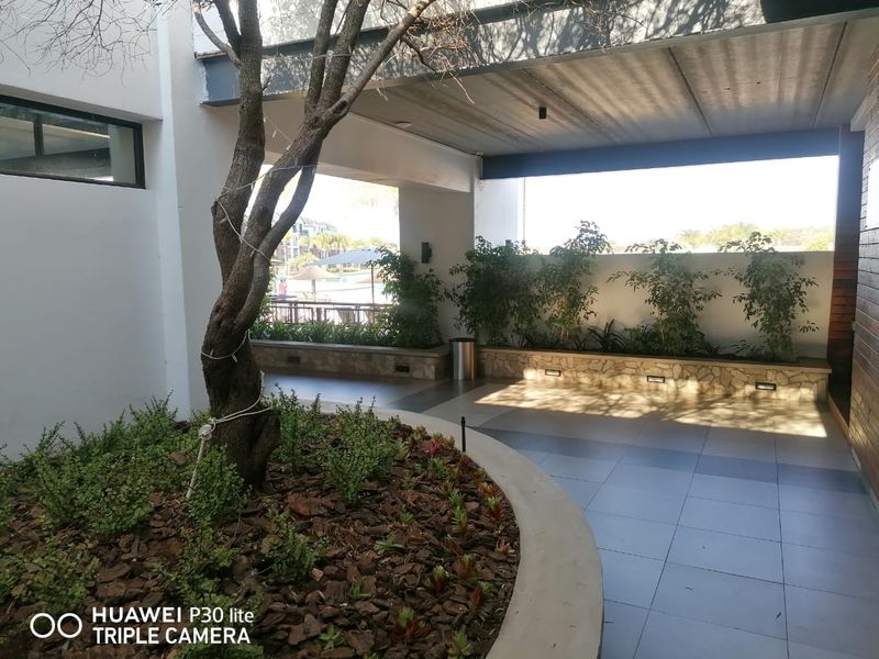 A spacious covered patio area featuring tiled flooring, built-in planter boxes, and recessed lighting, offering a pleasant outdoor transition space.