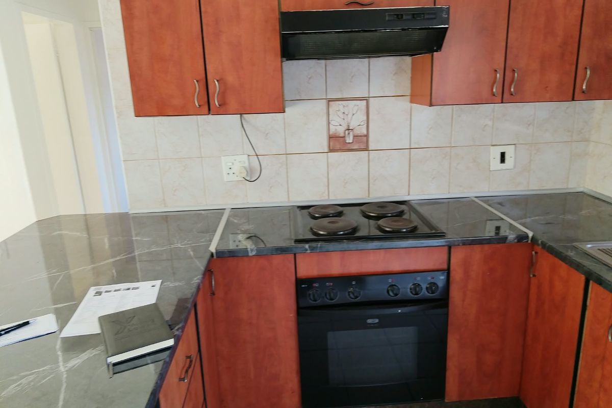 A functional kitchen featuring laminate cabinetry, marble-look countertops, a built-in electric oven, and a tiled backsplash.