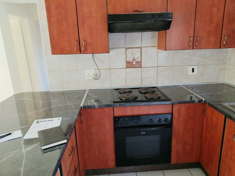 A functional kitchen featuring laminate cabinetry, marble-look countertops, a built-in electric oven, and a tiled backsplash.