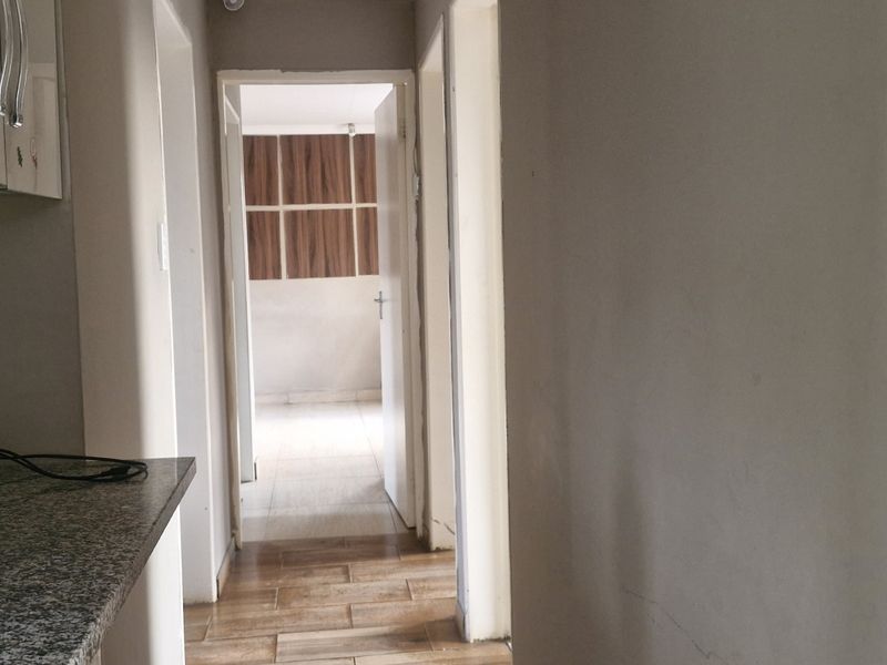 A view from a kitchen area looking into a hallway with tiled flooring and neutral wall finishes.