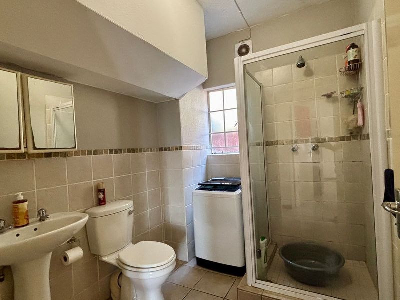 Functional bathroom featuring a pedestal basin, toilet, and a glass-enclosed shower with tiled finishes and an integrated extractor fan.