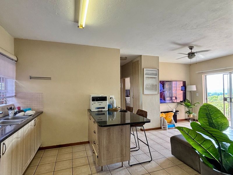 Open-plan living area featuring a kitchen with granite countertops, tiled flooring, and a sliding door leading to an outdoor space.