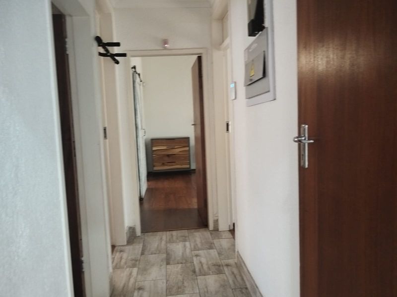 A functional hallway featuring tiled flooring and access to adjacent rooms, with a visible electrical distribution board mounted on the wall.