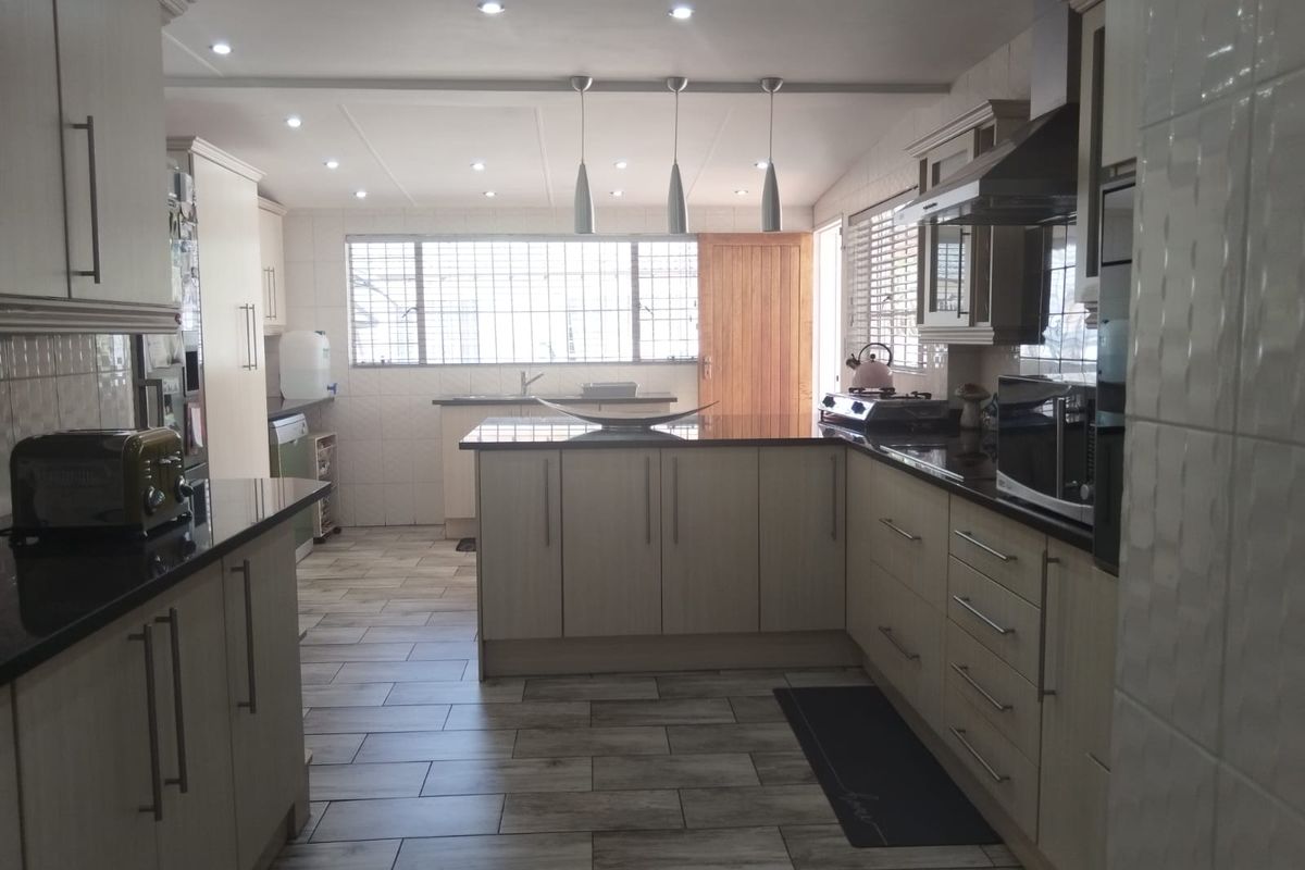 A well-appointed kitchen featuring extensive built-in cabinetry, granite countertops, modern recessed lighting, and durable tiled flooring with a functional layout.
