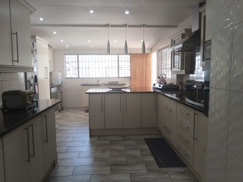 A well-appointed kitchen featuring extensive built-in cabinetry, granite countertops, modern recessed lighting, and durable tiled flooring with a functional layout.