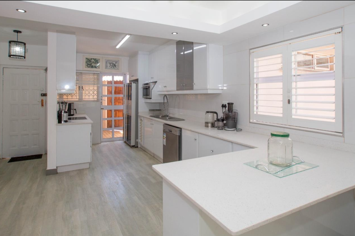 Modern kitchen featuring white cabinetry, quartz countertops, integrated appliances, and recessed lighting, offering a clean and functional workspace.
