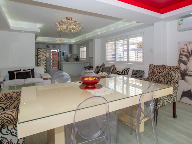 Spacious open-plan living and dining area featuring modern recessed lighting, cove ceiling details, laminate flooring, and an integrated split-system air conditioning unit.