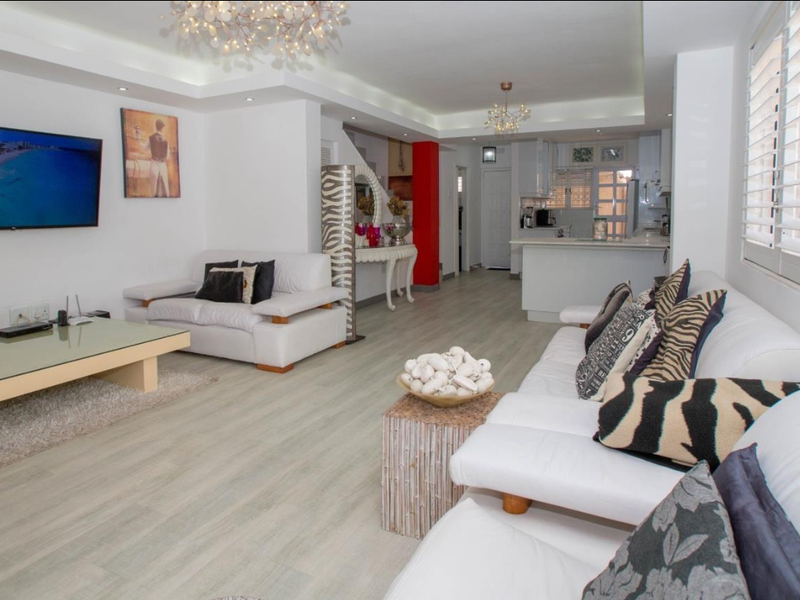 Spacious open-plan living area featuring modern laminate flooring, recessed ceiling lighting, and a functional kitchen with a central island and plantation shutters.