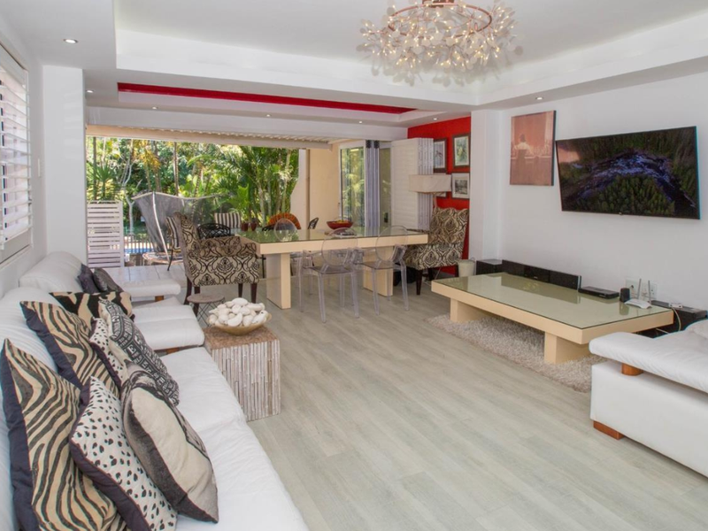 Spacious open-plan living and dining area featuring modern laminate flooring, recessed ceiling lighting, and large sliding glass doors opening to the outdoor space.
