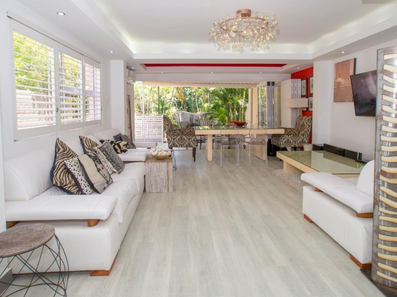 Spacious open-plan living and dining area featuring light laminate flooring, recessed ceiling lighting, and large sliding doors opening to a private outdoor space.
