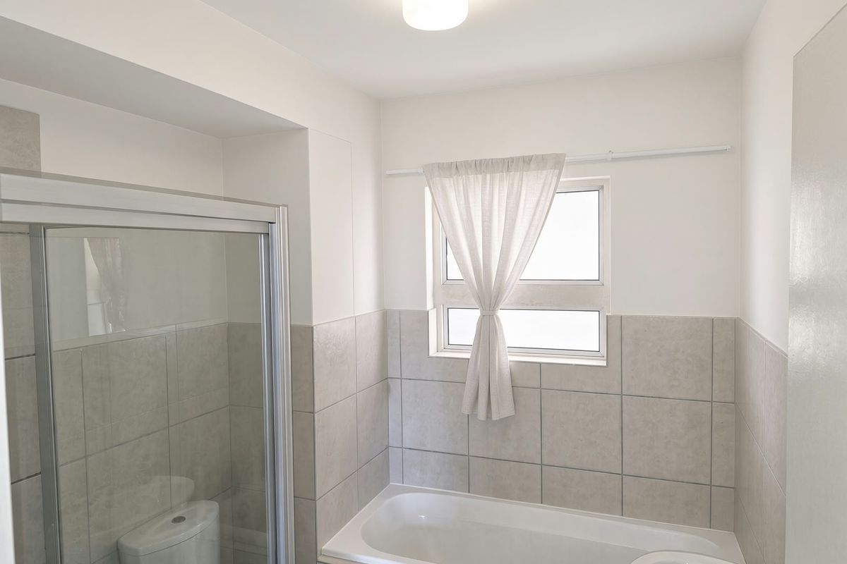 A clean and functional bathroom featuring a shower enclosure, a bathtub, and neutral wall tiling.