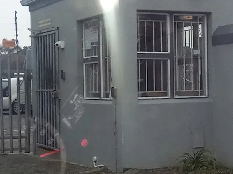 A secure guard house or entrance gate structure featuring security bars, surveillance cameras, and floodlighting, situated at the property entrance.