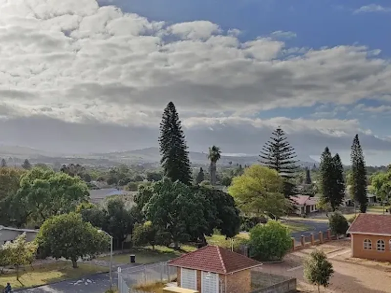 Elevated scenic view overlooking the surrounding neighborhood, trees, and distant hills from an apartment balcony.