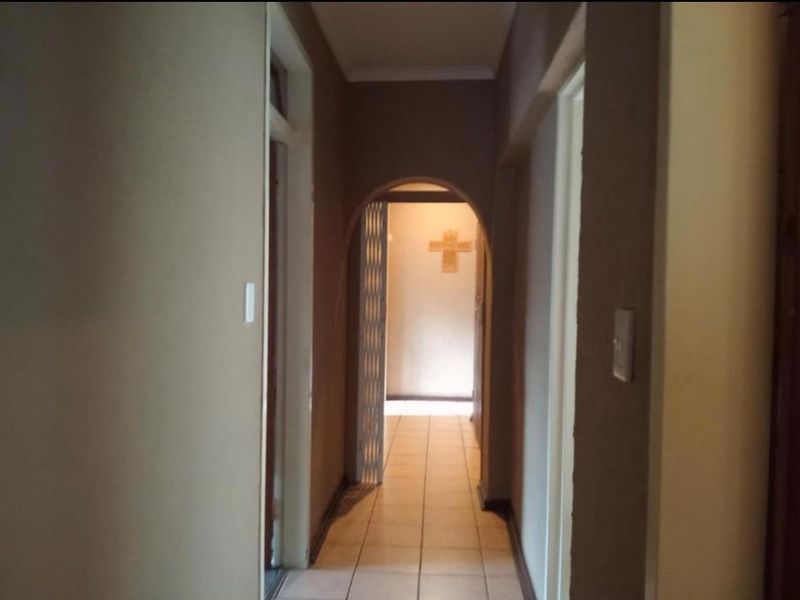 A functional hallway featuring tiled flooring and an arched doorway leading to an adjacent room.