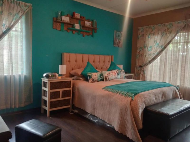 A bedroom featuring dark laminate flooring and dual windows with curtain rails, providing a functional space with potential for modern updates.