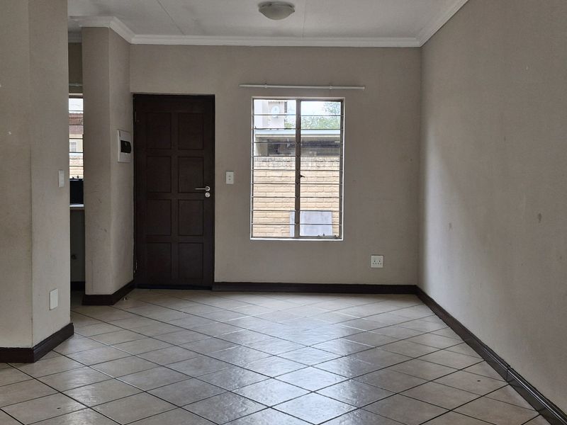 An open-plan living area featuring tiled flooring, a stone-clad breakfast bar, and neutral walls, offering a blank canvas for interior design.