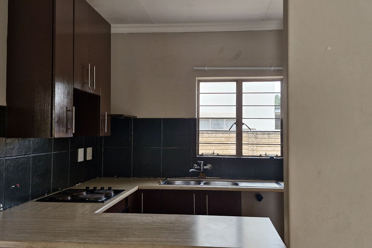 A functional kitchen featuring built-in cabinetry, a laminate countertop, a built-in hob, and a double sink with a tiled backsplash.