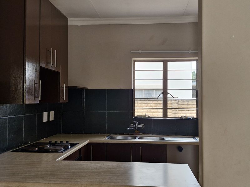 A functional kitchen featuring built-in cabinetry, a laminate countertop, a built-in hob, and a double sink with a tiled backsplash.
