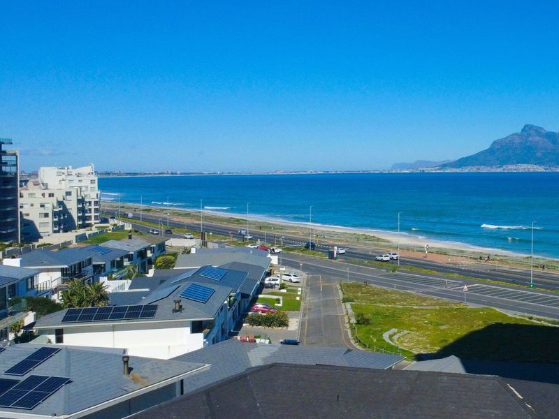 A panoramic coastal view overlooking the ocean, beach, and distant mountains, showcasing the prime location of the property.