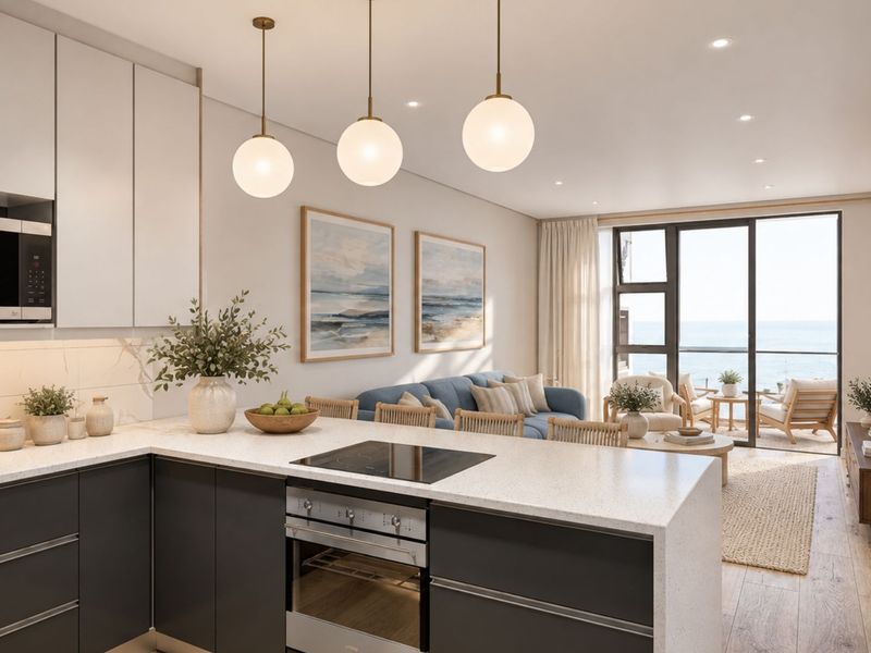 Modern open-plan kitchen and living area featuring sleek cabinetry, stone countertops, integrated appliances, and seamless access to a balcony with ocean views.