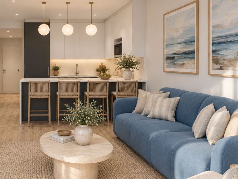 Modern open-plan living area featuring a sleek kitchen with stone countertops, integrated appliances, and recessed lighting, seamlessly flowing into a bright, comfortable lounge space.