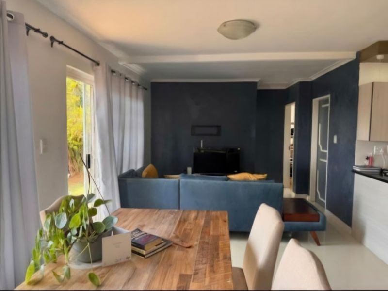 Open plan living and dining area featuring a sliding glass door to the garden and an adjacent kitchen with built-in cabinetry.