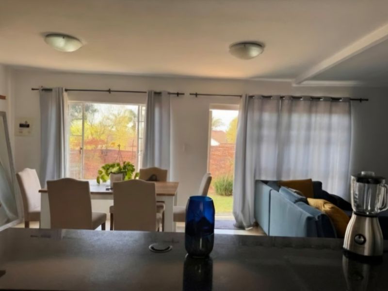 Open plan living and dining area featuring a kitchen island, large windows, and direct access to the rear garden through a sliding glass door.