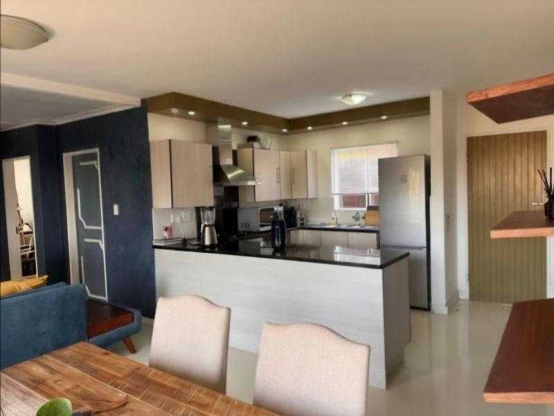 Open-plan kitchen and living area featuring modern cabinetry, granite countertops, and a breakfast bar, creating a functional and connected living space.