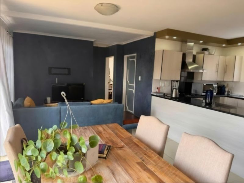 Open plan living and dining area featuring a modern kitchen with built-in cabinetry, extractor fan, and a breakfast bar island.