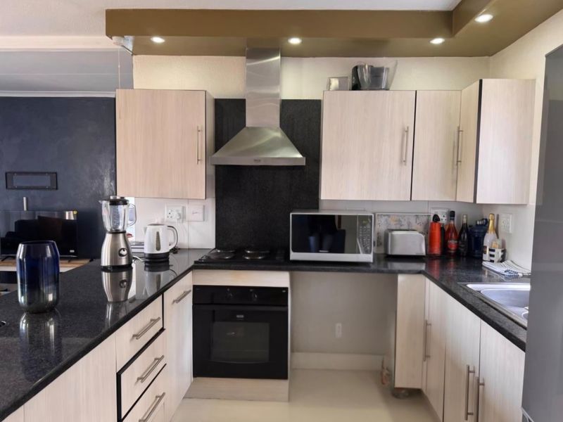 Functional kitchen featuring granite countertops, built-in oven, extractor fan, and light-toned cabinetry, offering a practical layout for daily meal preparation.