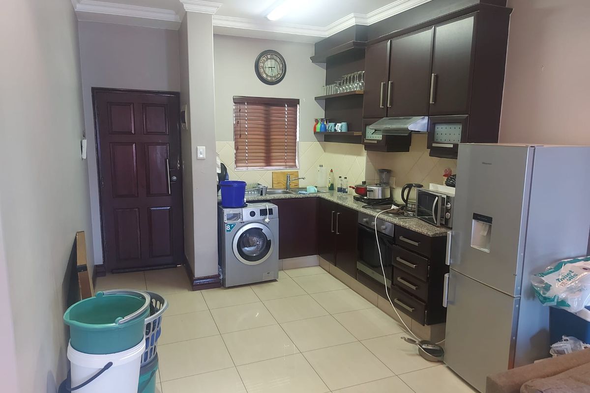 A functional kitchen featuring dark wood cabinetry, granite countertops, built-in oven, extractor fan, and tiled flooring, providing a practical workspace.