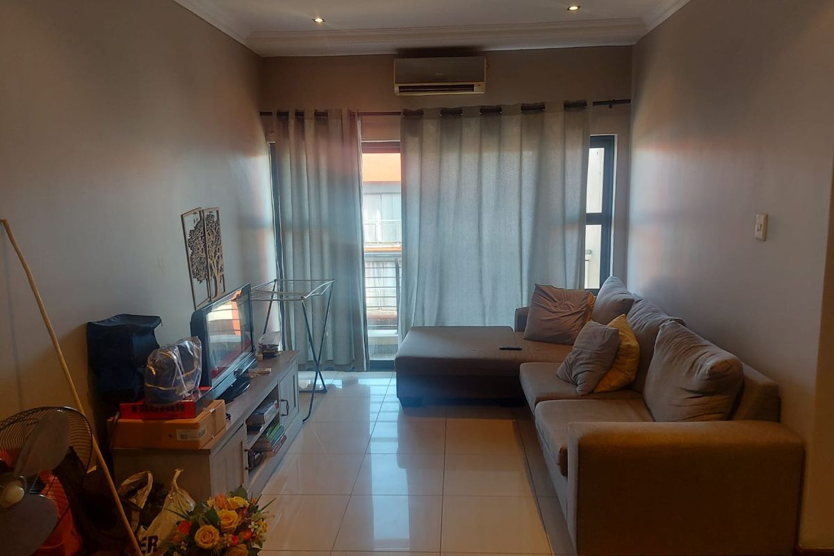 A living room featuring tiled flooring, a wall-mounted air conditioning unit, and a sliding glass door leading to an outdoor area.