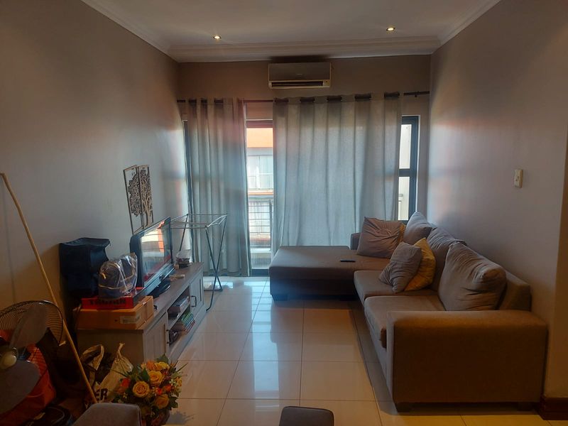 A living room featuring tiled flooring, a wall-mounted air conditioning unit, and a sliding glass door leading to an outdoor area.