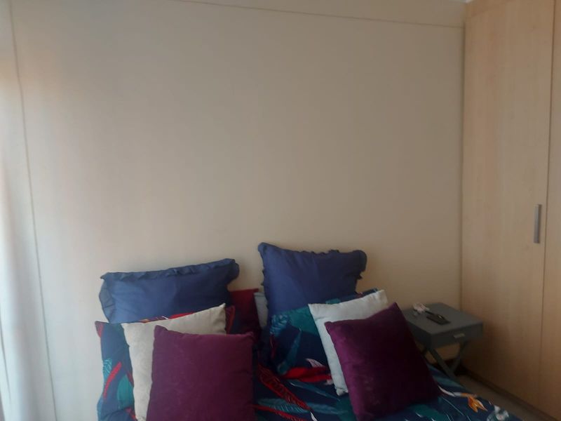 A bedroom featuring a built-in wardrobe with light wood finish and neutral wall tones.