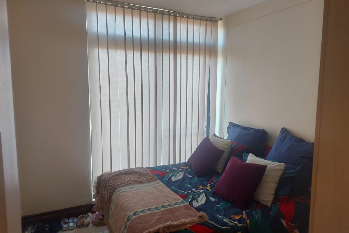 A standard bedroom featuring vertical blinds over a large window, providing natural light and privacy.