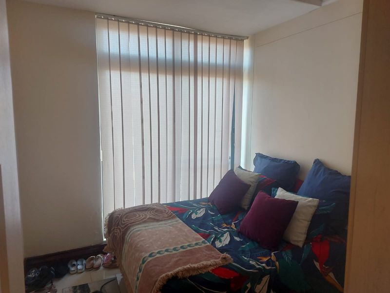 A standard bedroom featuring vertical blinds over a large window, providing natural light and privacy.