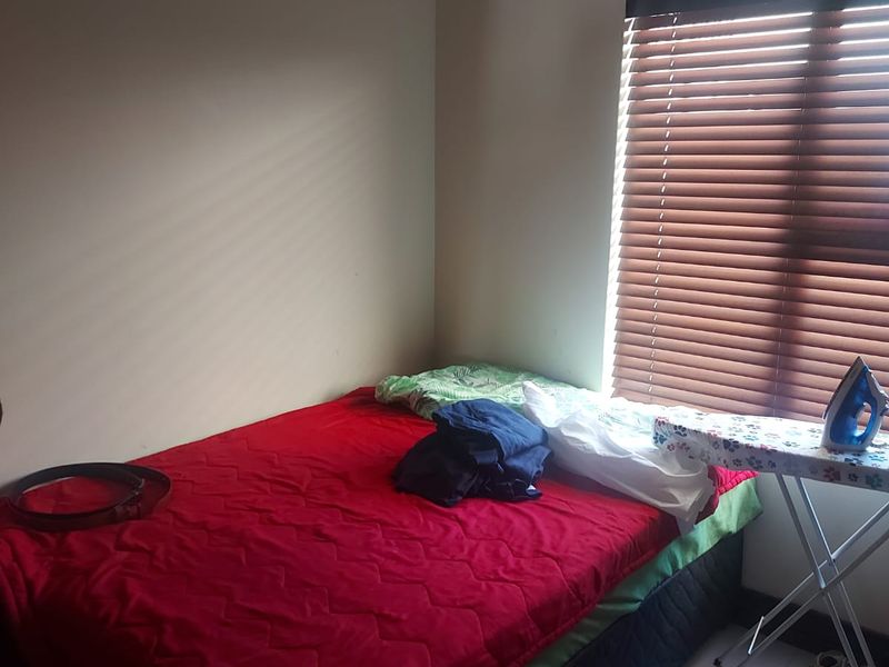 A bedroom featuring tiled flooring and brown venetian blinds, providing a functional space with natural light.