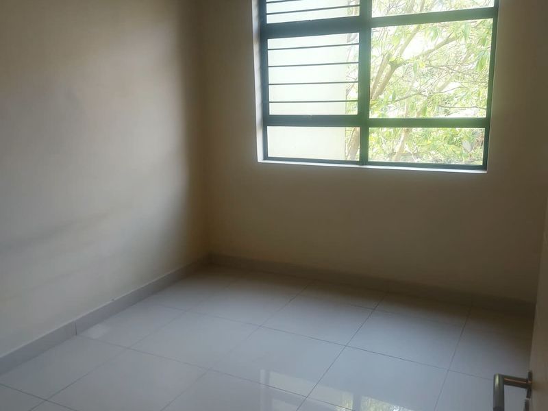 A bright, empty bedroom featuring neutral walls, polished floor tiles, and a window fitted with security bars.