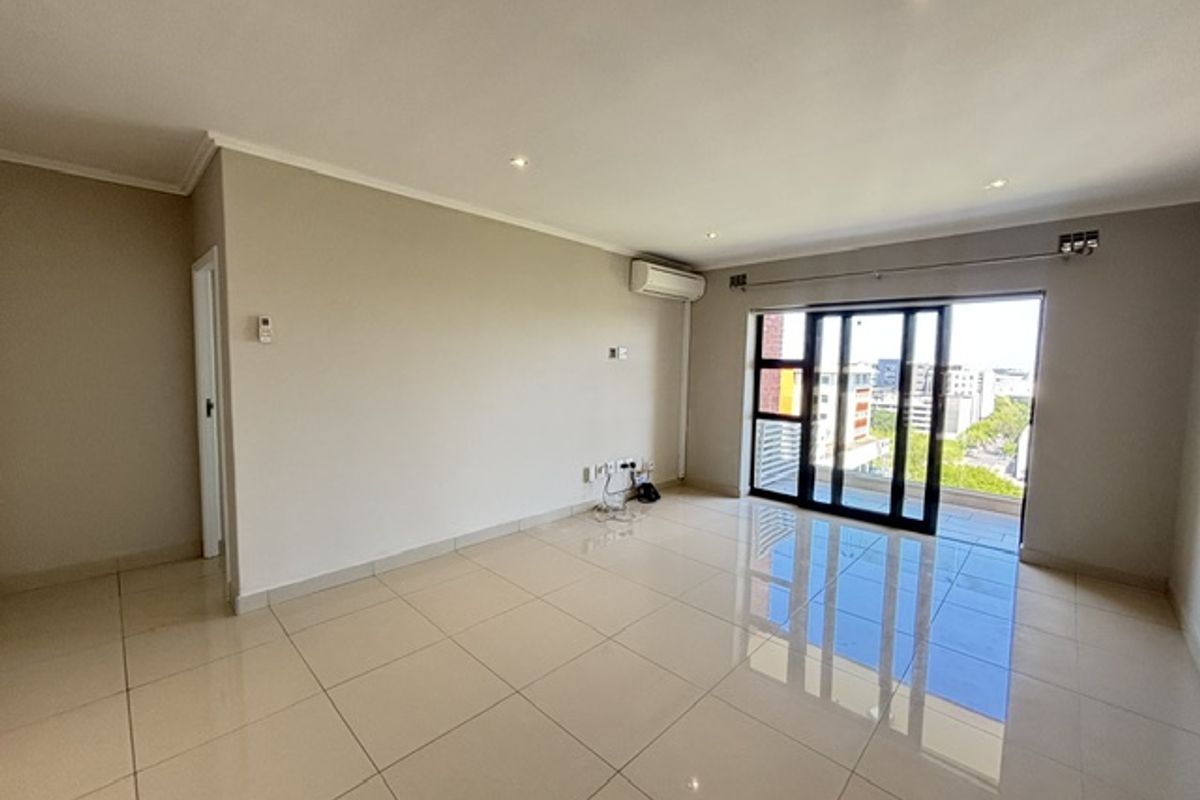 Spacious, light-filled living area featuring polished tile flooring, recessed lighting, and a large sliding glass door providing access to the balcony.