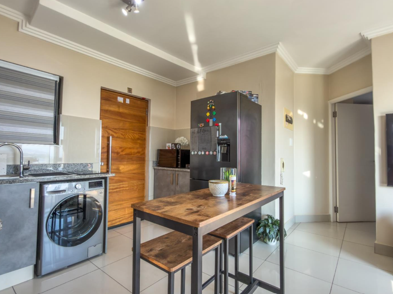 A modern kitchen featuring granite countertops, sleek under-counter cabinetry, tiled flooring, and elegant coved ceiling cornices, providing a functional and contemporary cooking space.