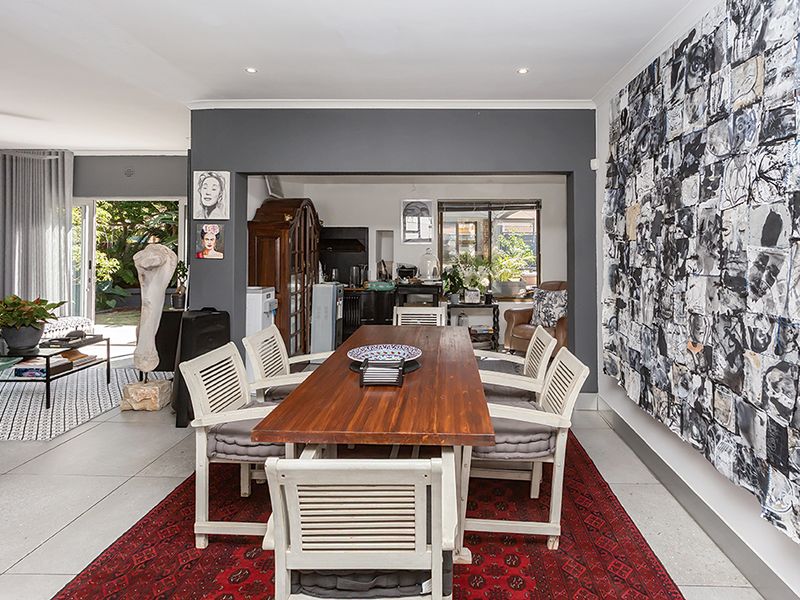 Spacious open-plan dining and living area featuring large format floor tiles, recessed lighting, and seamless access to the outdoor patio through sliding glass doors.