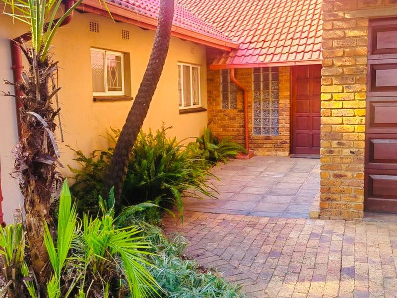 A well-maintained front entrance area featuring brick paving, a facebrick facade, and a classic tiled roof design.