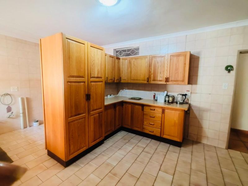 A functional kitchen featuring traditional wooden cabinetry, tiled flooring, and wall splashbacks, offering a classic layout with ample storage space.