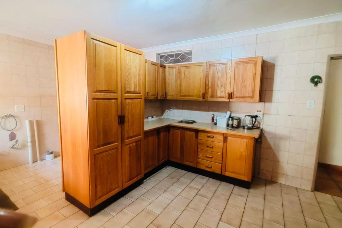 A functional kitchen featuring traditional wooden cabinetry, tiled flooring, and wall splashbacks, offering a classic layout with ample storage space.